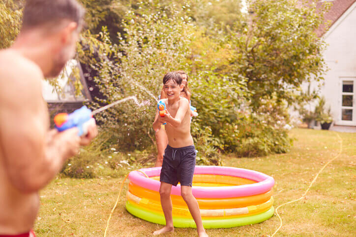 a father and son playing water sports in the garden