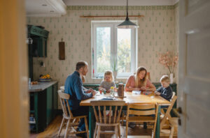 a young family sitting around a dining table in a kitchen