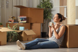 woman sitting on floor of new house surrounded by boxes